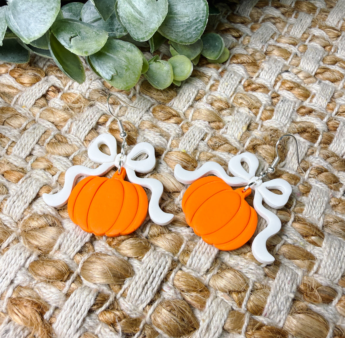 Orange pumpkin dangle earrings with oversized white bows and silver-tone hooks, cute fall statement jewelry for Halloween, Thanksgiving, and pumpkin patch outfits.