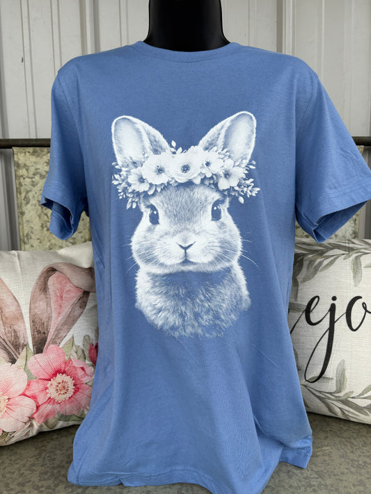 Blue Bella Canvas short sleeve t-shirt featuring a vintage-style bunny graphic with a floral crown in white print. Cute pastel Easter bunny tee for women with soft spring aesthetic and farmhouse-inspired design.