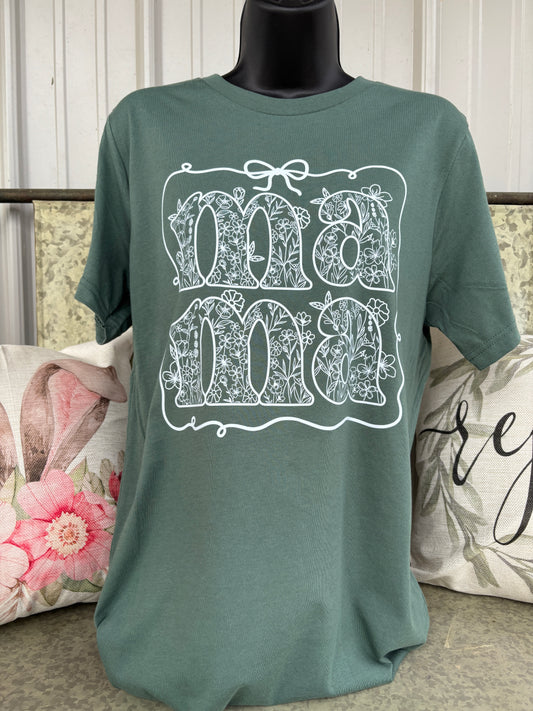 Bella Canvas® sage green graphic t-shirt featuring a white floral “mama” design with delicate wildflower details and bow accent. Trendy minimalist mom tee with feminine botanical artwork and soft boutique-style aesthetic.
