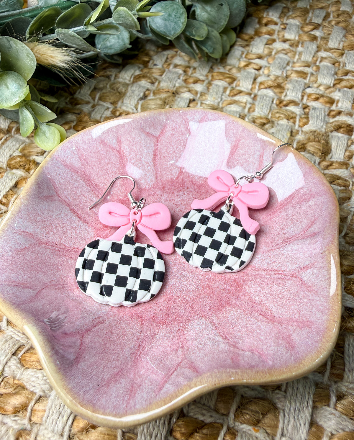 Pink bow checkered pumpkin dangle earrings featuring black and white checkerboard pumpkins with pastel pink bows and silver-tone hooks, trendy fall and Halloween jewelry.