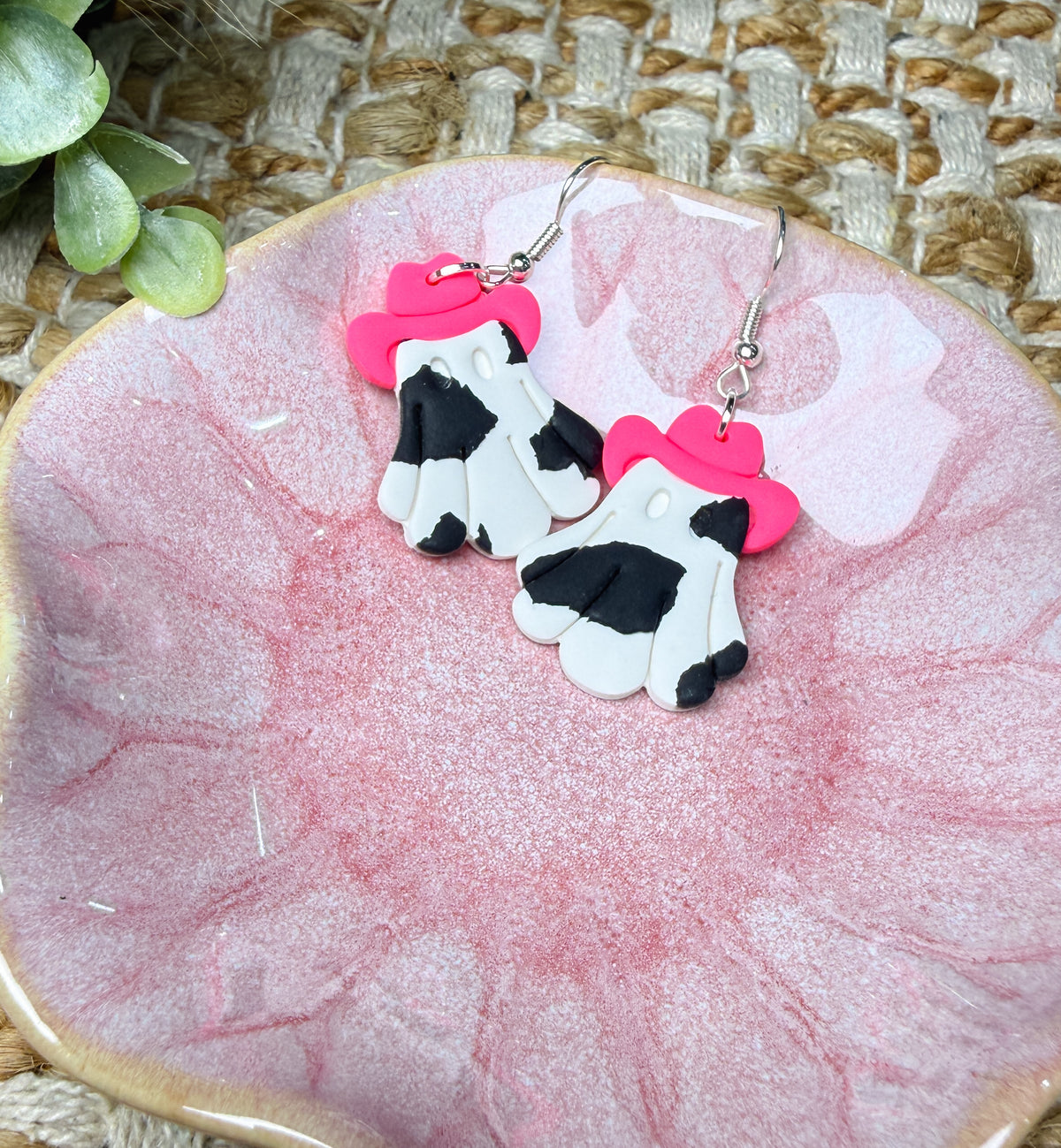 Cowgirl ghost Halloween dangle earrings featuring white ghosts with black cow print spots, bright pink cowboy hats, and silver-tone hooks. Cute western Halloween jewelry.